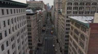 Hava görüntüleri New York sokaklarının hareketli görüntülerini yakalıyor, arabalar ve otobüsler trafikte hareket ediyor. Sokak deliklerinden yükselen buhar canlı şehir manzarasını güçlendiriyor.