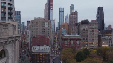 Flatiron Bölgesi 'nde Manhattan gökdelenleriyle çevrili Madison Meydanı Parkı' nı gösteren hava görüntüsü yumuşak ışıklandırma ve dinamik şehir atmosferiyle kentsel alacakaranlığı gözler önüne seriyor..