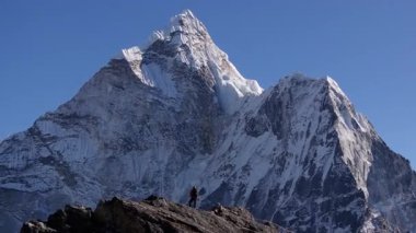 Dağcı Nangkarshang Tepesi 'nin tepesinde duruyor, devasa Everest Dağı' na karşı siluet, görkemli Himalaya manzarası ve Nepal vahşi doğasını gözler önüne seriyor..