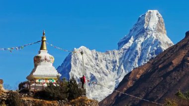 Dağcı ahşap stupaya renkli bayraklar asıyor, Ama Dablam dağı Everest Bölgesi, Nepal 'in arkasında yükseliyor..