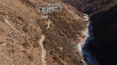 Yürüyüşçüler ve tırmanışçılar için popüler bir durak olan sığ köy, Nepal 'de nefes kesici bir zemin sağlayan görkemli Everest Dağı ile bir nehir tarafından oyulmuş bir vadide dinleniyor..