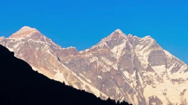 Himalaya arazisinde karların içinden yükselen devasa Everest Dağı, uzak Nepal dağlarında beyaz zirveli görkemiyle masmavi gökyüzünü deldi..