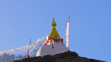 Dingboche, Nepal 'deki görkemli Himalaya dağ panoramalarına karla vurgulanan parlak beyaz dualar, parlak bayraklar, altın kule.