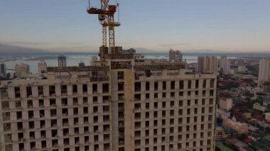Manila 'da terk edilmiş bir inşaat alanının arka planında vinçler ve şehir silueti olan hava görüntüsü kentsel kalkınma projelerini gözler önüne seriyor..