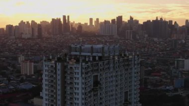 Manila silueti üzerinde sakin bir gündoğumu görüntüsü, terasın üstünde bir konut binası ve sıcak şehir manzarası var. Şehir manzarası ve seyahat içeriği.