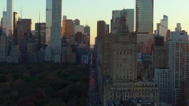 Sıcak gün batımı ışığı, şehir merkezindeki Manhattan gökdelenlerini sarar. Buna San Remo da dahil. Gökyüzünü aydınlatır. Arabalar Central Park 'ın güneyine gidiyor.
