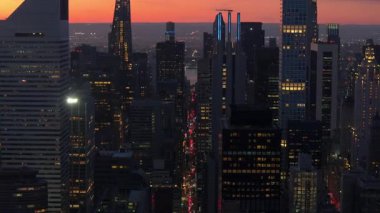 Güneş Manhattan 'da batarken, turuncu ve mavi gölgeler gökyüzünü boyuyor. Yükselen gökdelenler, aşağıdaki hareketli şehir manzarasının üzerine sıcak bir parıltı saçıyor..