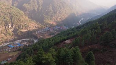 Himalaya bölgesinde yuva yapmış, dağlık Nepal köyü Phakding 'i kuşatan sabah sisi, yürüyüşçülerin ana iklimlenme noktası olarak hizmet veriyor..