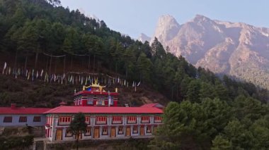 Nepal 'deki yemyeşil Himalaya dağ ormanları arasında manevi bağlılığı simgeleyen, Budist manastırı yakınlarında dalgalanan canlı dua bayrakları..