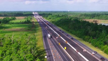 Bol yeşillik ve inşaat konileri olan hareketli bir Amerikan otoyolunun hava manzarası. Temiz gökyüzü ve canlı manzara manzarayı güzelleştirir..