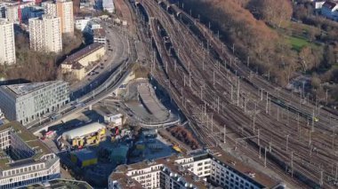 Alman şehrindeki karmaşık demiryolu ağının yüksek açılı görüntüsü, yakınsayan raylar, kentsel gelişim ve yeşil alanlar sergileniyor.