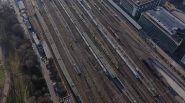 Stuttgart Hauptbahnhof 'ta park halindeki trenlerin yüksek açılı görüntüsü, demiryolu altyapısını parlak platform tasarımı ve kentsel geçiş peyzajıyla vurguluyor.