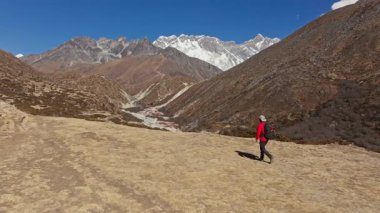 Himalaya tepelerinde, Shomare 'den Dingboche Route' a, karlarla kaplı zirvelerin arasında dik dağlarda yürüyen yalnız yürüyüşçülerin hava görüntüleri..