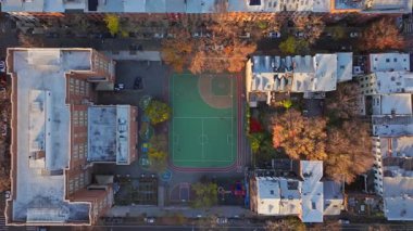 Havadan bakıldığında okul bahçesi ve oyun parkı New York şehrinin ortasında, sonbahar renkli ağaçlar ve kentsel mimari unsurlarla çevrili..