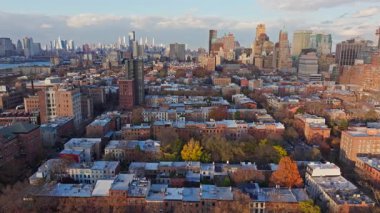 Brooklyn 'deki alçak binaların ve renkli sonbahar ağaçlarının havadan görünüşü ve arka planda Manhattan silüeti..