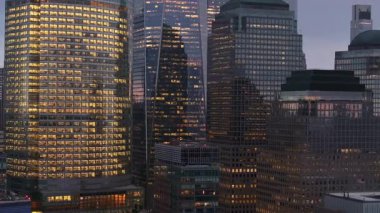 Hava görüntüsü, alacakaranlık şehir manzarasına karşı parlayan Aşağı Manhattan gökdelenlerini, akşamları parlayan Mali Bölge 'yi yakalıyor..