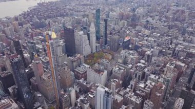 Manhattan şehir merkezini gözler önüne seren hava manzarası, yoğun gökdelenleri ve günışığı altındaki modern şehir mimarisini vurguluyor..