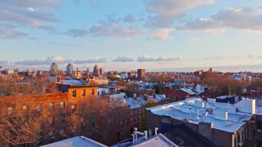Altın günbatımı ışınları Brooklyn 'deki yerleşim yerlerinin çatılarını yıkıyor, sakin kentsel manzarayı gözler önüne seriyor..