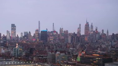 Manhattan 'ın parlayan siluetini yakalayan hava manzarası aydınlanmış gökdelenlerin mimari karmaşıklığa sahip alacakaranlık şehir manzarasına karşı yükseldiğini gösteriyor..
