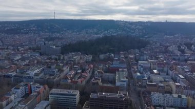 Stuttgart şehir manzarası, eski Allianz Binası, Televizyon Kulesi 'nin de dahil olduğu mimari manzarayı gözler önüne seriyor. Geniş bulutlu gökyüzü altında, ağaçlarla kaplı yeşil tepelerin arasından yükselen.