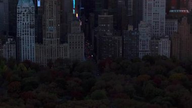 Central Park 'ın 57. caddesindeki vitrinlere bakan kamera, Manhattan' ın göbeğindeki yüksek binaları çarpıcı bir günbatımına karşı aydınlatıyor, canlı bir şehir manzarası yaratıyor..