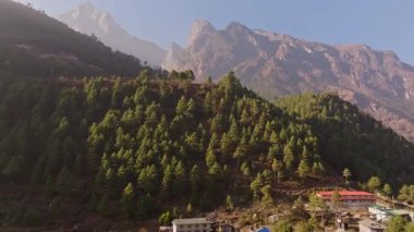 Yeşillik yeşil tepeler, sık çam ormanları, el değmemiş Himalaya dağlarındaki Phakding köyünde yuva yapmış uzak yapılar üzerindeki hava perspektifi..