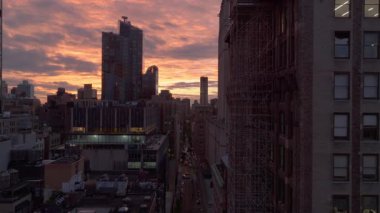 Hava görüntüleri, gün batımında canlı bir New York caddesi yakalıyor. Arabalar, turuncu ve pembe gökyüzünün çarpıcı zeminine karşı trafikte zikzak çiziyor..