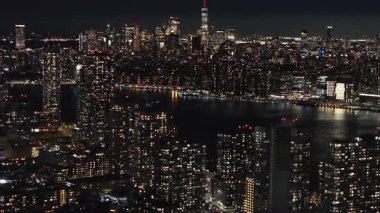Aşağı Manhattan ve Doğu Nehri 'nin geceleri hava manzarası. Kamera New York gökdelenleri üzerinde hareket ediyor. Şehir ışıklarının çarpıcı manzarasını sunuyor..