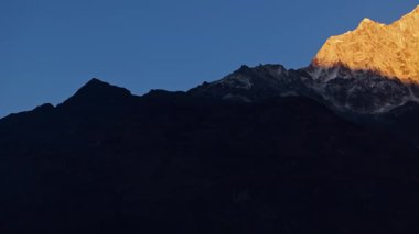Altın güneş ışığı, Himalaya 'nın Nepal dağ manzarasında sabahın erken saatlerinde Everest Dağı' nın görkemli karla kaplı tepelerini yavaş yavaş ortaya çıkarıyor..