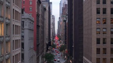 Manhattan şehir merkezinin pencerelerinin hava manzarası, alacakaranlık sırasında yüksek binaların altındaki araç hareketlerini takip etmek, şehir merkezindeki mimari ihtişamı vurgulamak..