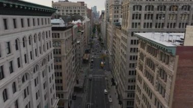 Hava görüntüleri New York sokaklarının hareketli görüntülerini yakalıyor, arabalar ve otobüsler trafikte hareket ediyor. Sokak deliklerinden yükselen buhar canlı şehir manzarasını güçlendiriyor.