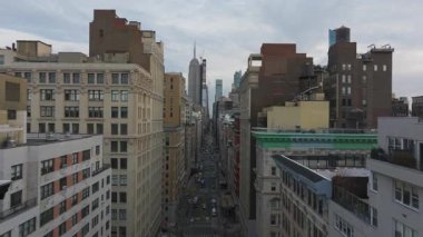 Gökyüzü görüntüsü, arka planda ikonik Empire State Binası kuleleri dururken, sarı taksilerle dolu canlı bir New York caddesini vurguluyor..