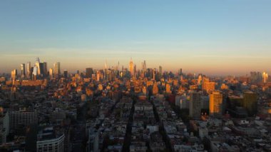 Sıcak güneş ışığı Manhattan şehir merkezini ve New York şehrinin ufuk çizgisini sarar. Güneş ufukta batarken yükselen gökdelenlerden uzayan gölgeler yaratır..