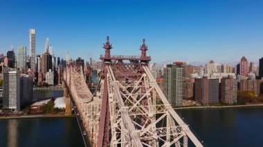 Gökdelenler Queensboro Köprüsü üzerinde süzülüyor, ikonik gökdelenleri vurguluyor ve Manhattan 'ın ortasındaki canlı şehir, New York City gökyüzü altında sonbaharda berrak mavi bir gökyüzünün altında gökyüzü var..