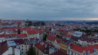 Prag 'ın çatılarında süzülen kamera canlı binaları ve kırmızı kiremitli çatıları gün batımında yumuşak pembe ve portakallarla gökyüzünü boyarken gösteriyor..