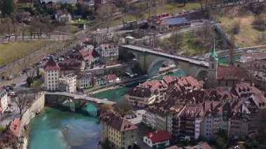 Tarihsel Bern şehir manzarası Nydeggbrucke köprüsünün turkuaz Aare nehrine yayılışını gösteriyor, yukarıdan bakıldığında ortaçağ kentsel manzarasını ortaya çıkarıyor.