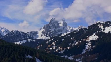 İsviçre Alplerindeki Gstaad 'ın nefes kesici hava manzarası, karlı tepeler, çam ormanları ve kışın açık mavi bir gökyüzü..