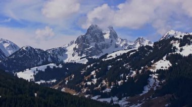 Kar örtülü dağların ve İsviçre Alpleri 'ndeki Gstaad' ı çevreleyen vadilerin eşsiz perspektifinden bir tripoda sahip hava manzarası..