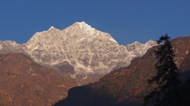 Everest Dağı 'na altın parıltı saçan güneş ışığının havadan görünüşü Nepal Himalaya bölgesindeki sonsuz yeşil ormanın üzerinde yükseliyor..