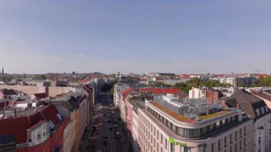 Berlin 'in kuş bakışı manzarasında şehir binalarının ikonik kırmızı çatıları, yeşil ağaçlar ve aşağıdaki caddede giden araçlar yer alıyor. Berlin, Almanya 2.2.24