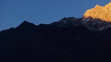 Altın güneş ışığı, Himalaya 'nın Nepal dağ manzarasında sabahın erken saatlerinde Everest Dağı' nın görkemli karla kaplı tepelerini yavaş yavaş ortaya çıkarıyor..
