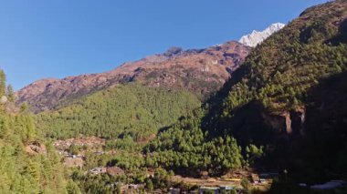 Nepal 'de yaz güneşinin altında Himalaya manzaraları boyunca el değmemiş doğal güzellikleri gösteren yemyeşil vadi arazilerini kaplayan dağ sıralarının havadan görünüşü..