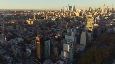 New York 'un Aşağı Doğu Yakası' nın havadan manzarası Manhattan şehrinin altın gün batımı parıltısıyla yıkanması sokaklar üzerinde yükselen gökdelenler ve yeşil alanlar..