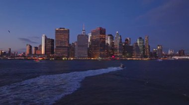 Sağlam bir römorkör, belirgin bir iz bırakıyor. Akşamları aşağı Manhattan ufuk çizgisine doğru kayıyor. Benzersiz bir hava tripod perspektifinden..