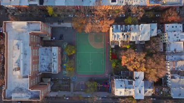 Havadan bakıldığında okul bahçesi ve oyun parkı New York şehrinin ortasında, sonbahar renkli ağaçlar ve kentsel mimari unsurlarla çevrili..