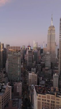 Dikey paneller, Empire State Binası 'nın gün batımında New York şehrinin ufuk çizgisinde zarafetle yükseldiğini gösteriyor..