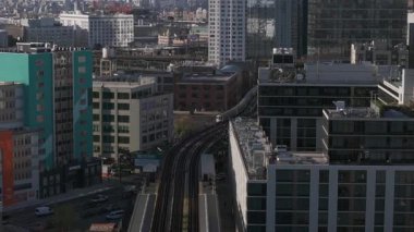 Havadan bakıldığında, New York 'un mimari manzarasında yükselen metro treni, parlak güneş ışığı altındaki binalar arasında süzülüyor..