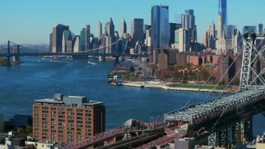 Kameralar Williamsburg, Brooklyn 'deki yerleşim alanının üzerinde kayarken, arka planda One Domino Square Condominium ve modern Manhattan gökdelenlerinin yükselişini gösteriyor..