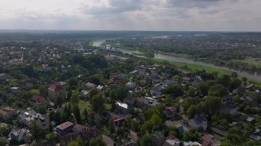 Havadan bakıldığında Neris Nehri 'nin Kaunas, Litvanya' da süzüldüğünü, bulutların parlak bir gökyüzünde tembelce sürüklendiğini, şehirlerin canlı manzarasını ve kentsel mimarisini vurguladığını görüyoruz..