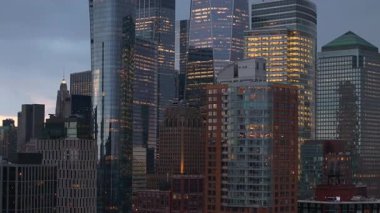 Manhattan gökdelenlerinin havadan kapatılması altın ışıkla parıldıyor, cam yüzeyler hareketli şehir manzarası boyunca sıcak alacakaranlık renklerini yansıtıyor..